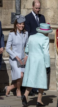 two women in blue dresses and hats are talking to each other while another woman is walking behind them