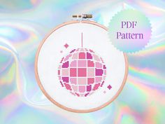 the cross stitch pattern is in pink and white, with a circular design on it