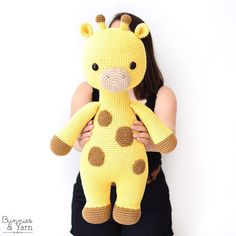 a woman holding a crocheted giraffe stuffed animal in front of her face