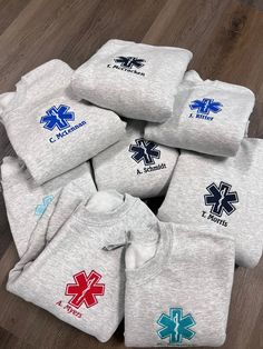 a pile of t - shirts with medical symbols on them sitting on top of a wooden floor