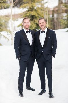 two men in tuxedos standing together in the snow