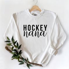 "ABOUT THE CREWNECK SWEATERS: This heavy blend unisex sweatshirt is made from 60/40 polyester/cotton. Features a unisex, comfy-fit, which is perfect for lounging, heading to the gym or running errands like heading to hockey practice or groceries! Sizes: S, M, L, XL, 2XL (fit a tad large on a woman, as they are UNISEX) We ask that you please check the measurements prior to ordering. Hockey Nana Sweater, Hockey Nana Sweatshirt, Grandma Christmas, Nana Gift, Crewneck Sweatshirt, Canadian Made, Gift for Her, Gift for Nana HOW TO ORDER: 1. Select the size and colour of the shirt you would like. 2. Add the quantity of each shirt you would like and then click \"Add to Cart\" 3. Please leave us any additional information in the notes to seller section 4. Submit Order. This listing is for ONE sweat Grandma Sweater, Hockey Sweatshirts, Grandmas Christmas, Nana Shirts, Christmas Gifts For Grandma, Nana Gifts, Gildan Sweatshirts, Comfy Fits, Running Errands