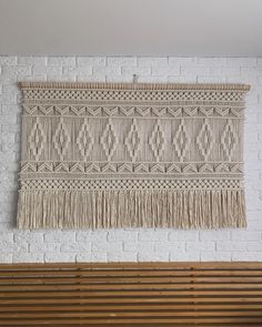 a wall hanging on the side of a white brick wall next to a wooden bench