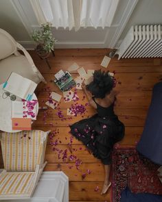 a woman is sitting on the floor surrounded by confetti and books as she looks down