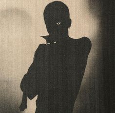 a black and white photo of a person in the shadows