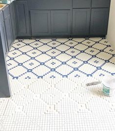 a bathroom with blue and white tiles on the floor next to a sink, toilet paper and brush