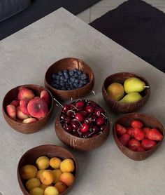 several bowls filled with different types of fruit on top of a white countertop next to a couch