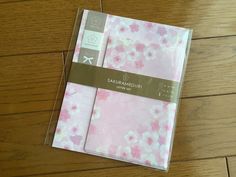 a pink and white flowered notebook on a wooden floor