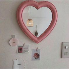 a heart shaped mirror mounted to the side of a wall next to a light switch