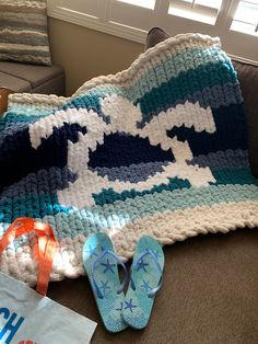 a crocheted blanket and pair of flip flops on a couch