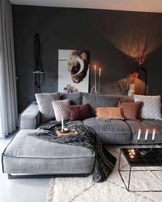 a living room with grey couches and pillows on top of the sofa is decorated with candles