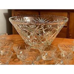 a glass bowl sitting on top of a wooden table next to other bowls and glasses