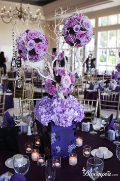 the centerpieces are arranged in purple flowers and branches, with candles on each side