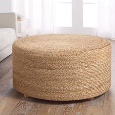 a large round jute ottoman sits on the floor