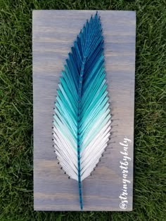 a blue and white feather sitting on top of green grass