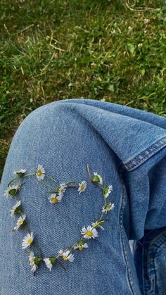 a pair of jeans with daisies in the shape of a heart on their lap