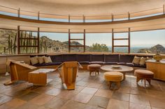 a living room filled with lots of furniture and large windows overlooking the mountain range in the distance