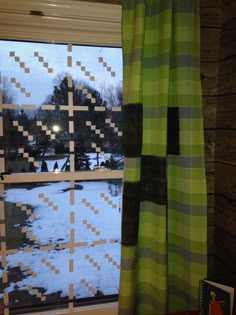 a window that has some curtains on it in front of a snow covered field outside