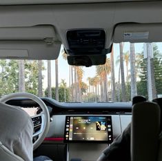 the interior of a car with palm trees in the background and a touch screen on the dashboard