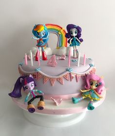 a birthday cake with three little pony dolls on top