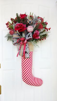 a christmas stocking hanging on the front door decorated with flowers and candy canes