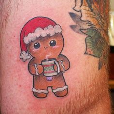 a man with a gingerbread tattoo on his leg wearing a santa hat and holding a cup