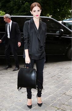 a woman carrying a black bag while standing next to a car