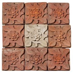 several square tiles with flowers and leaves on them, all made out of red clay