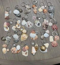 a collection of seashells are arranged on a wooden table with keychains