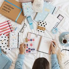 a woman is writing on her notebook while surrounded by stationery and other things she's doing