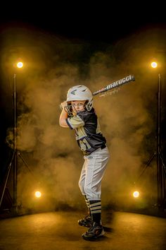 a baseball player holding a bat while standing on a stage with lights in the background