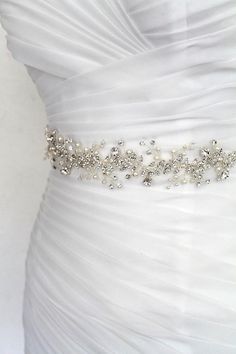 a bridal belt with pearls and crystals on the waist, attached to a wedding dress