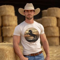 Experience the beauty of the wild west with this Rearing Horse at the Beach tee. Featuring a majestic rearing horse against a stunning backdrop of sun, sand, and surf at sunset, this unique design brings a bold western vibe to any look. Be the envy of the town! Cowboy Attire, Cowboy Outfit For Men, Mens Haircuts Short Hair, Cowboys Men, Western Outfits Men, Beach Tee, Cowboy Pictures, Just For Men, Cowboy Outfits