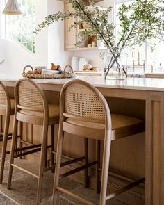 a kitchen with wooden cabinets and stools next to an island counter topped with plants