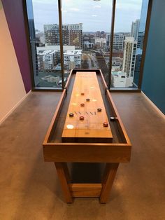 a wooden table in front of a window with an electronic device on it and some lights hanging from the ceiling