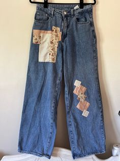 an old pair of jeans with patches on them hanging from a hanger against a wall