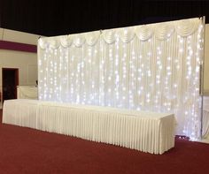 a banquet room with white drapes and lights on the wall, along with red carpeting