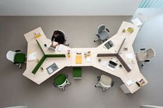 an overhead view of a table with chairs and laptops on it, in the middle of a room