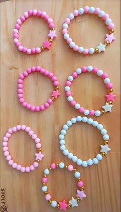 six bracelets with pink, white and blue beads sitting on top of a wooden table