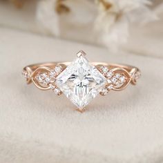 an engagement ring with a princess cut diamond in the center, surrounded by white flowers