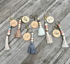 six different key chains with tassels and personalized tags on them sitting on a wooden surface