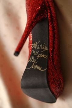 a red high heeled shoe with writing on the side and heels that say, there's no place like home