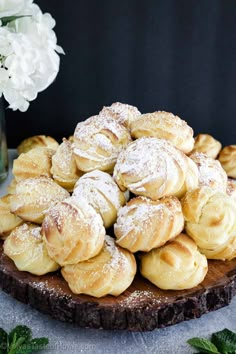 a pile of powdered sugar cookies sitting on top of a wooden board next to flowers