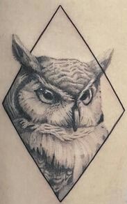 an owl tattoo on the back of a woman's shoulder