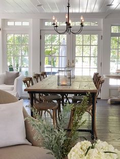 a dining room table surrounded by chairs with candles on them and flowers in vases