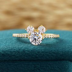 a yellow gold ring with an oval cut diamond in the center on top of a blue velvet cushion