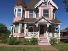 a pink victorian house with white trim and stairs