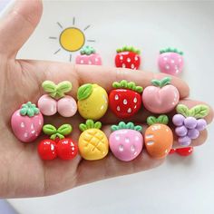 a hand is holding some tiny fruit charms