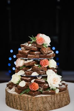 a wedding cake made out of cookies and flowers on a tree stump with blue lights in the background