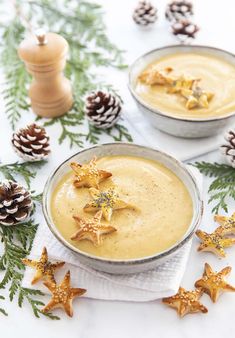 two bowls filled with food sitting on top of a table next to pine cones and christmas decorations